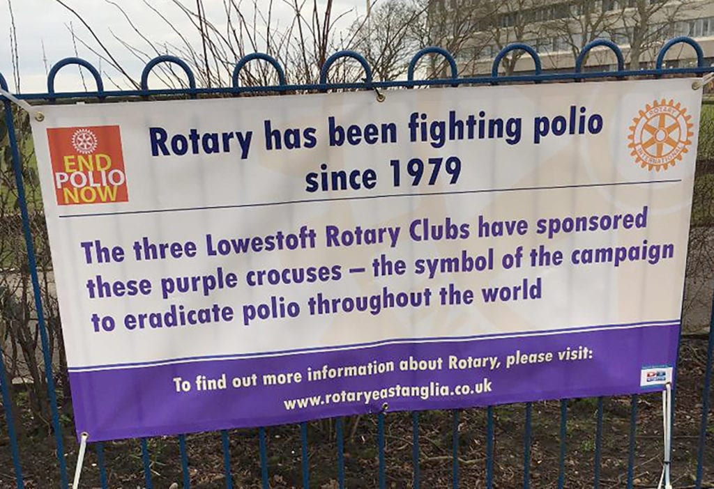 Photograph of a Rotary fighting Polio banner attached for a black metal fence railing